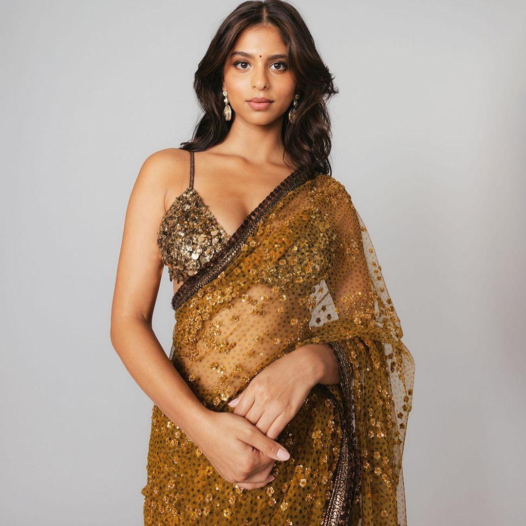 Suhana Khan wore a stunning golden sheer saree designed by Sabyasachi, pairing it with a heavily embellished blouse that had a deep neckline. To complement her outfit, she accessorized with kundan earrings and a glamorous golden clutch.