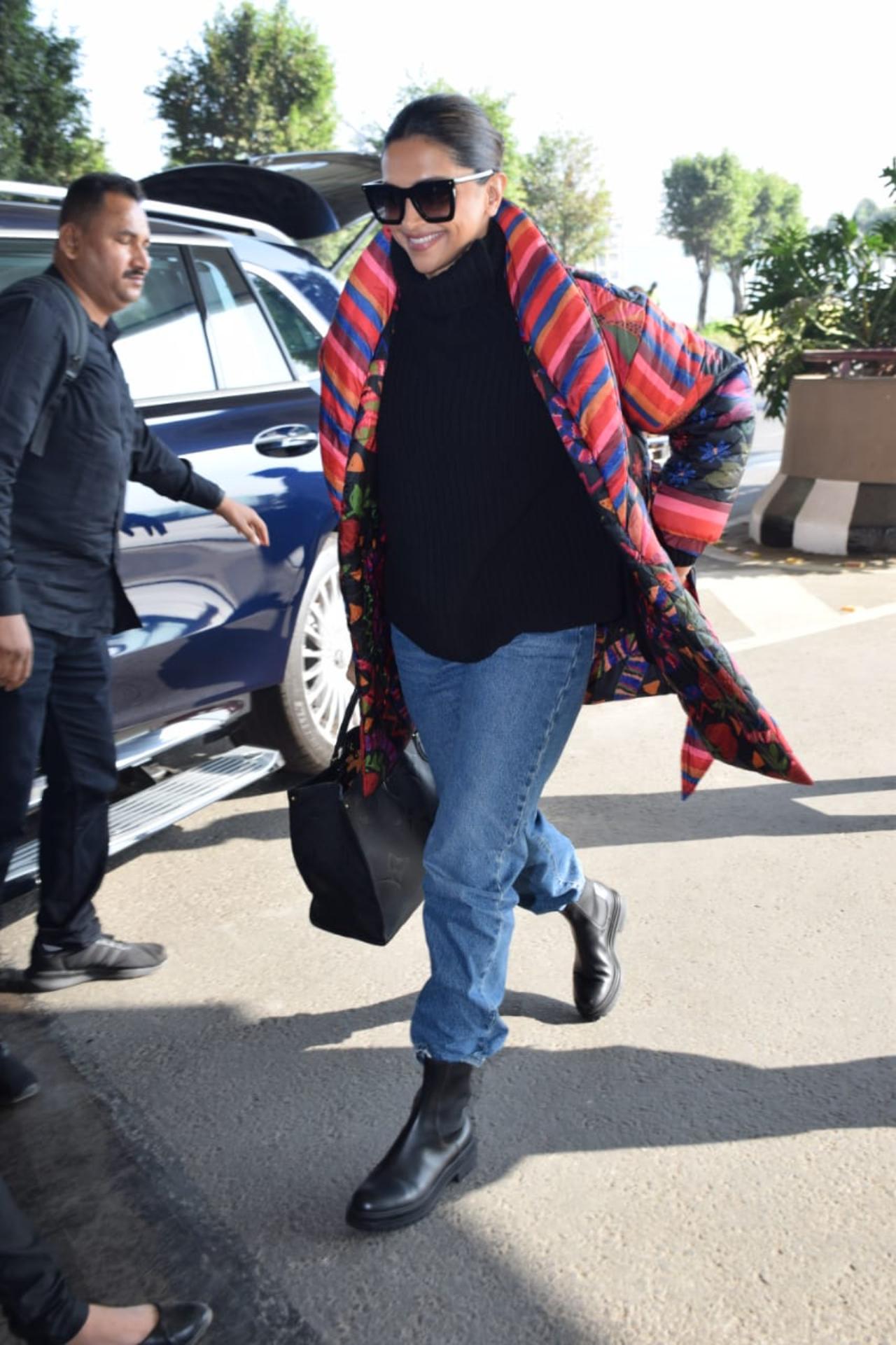 Deepika Padukone arrived at the airport in a black top and blue denims paired with black boots and a long colourful jacket. She had her hair tied in a bun and flashed a big smile before entering the gate