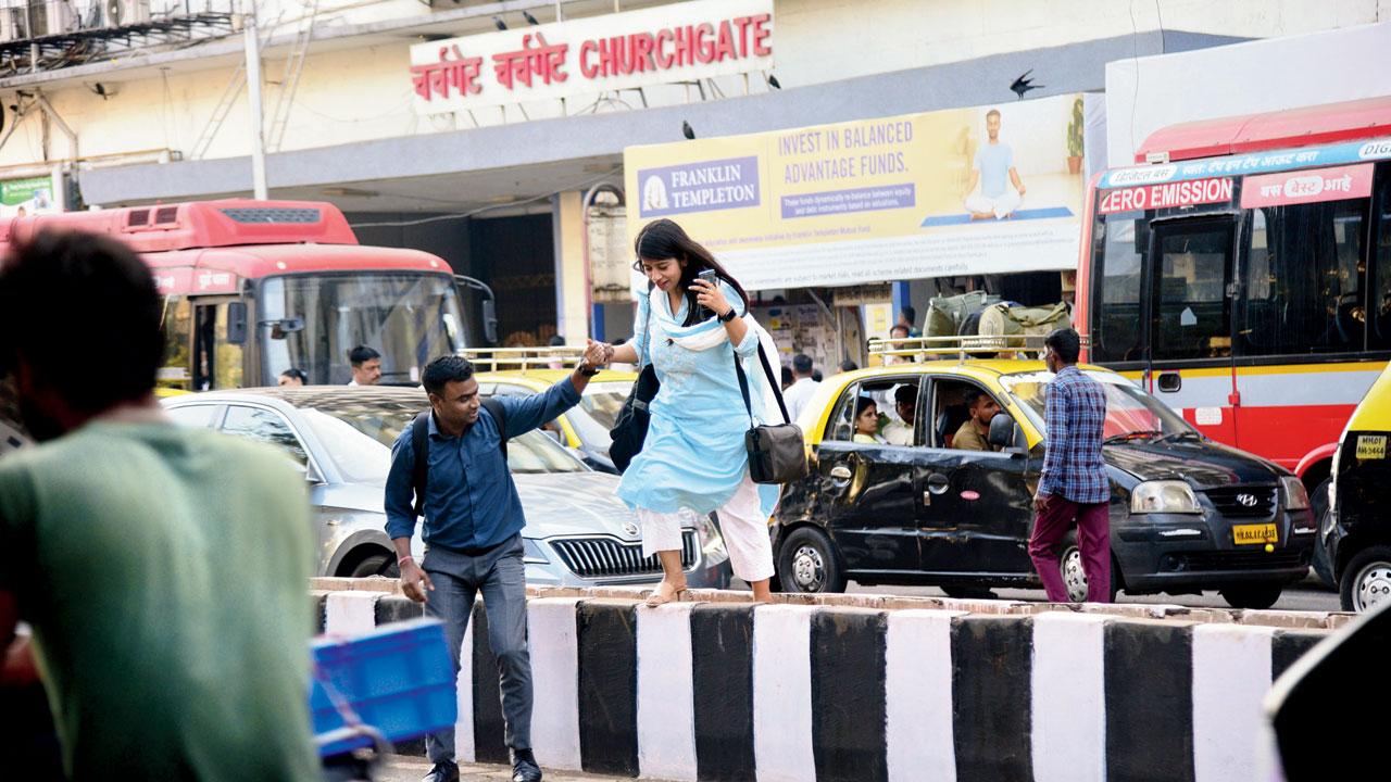 Pedestrians climb over a divider outside Churchgate station