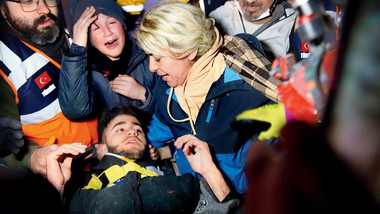 Rescuers and his mother surround Adnan Mohammet Korkut after he was rescued in Gaziantep, Turkey Friday