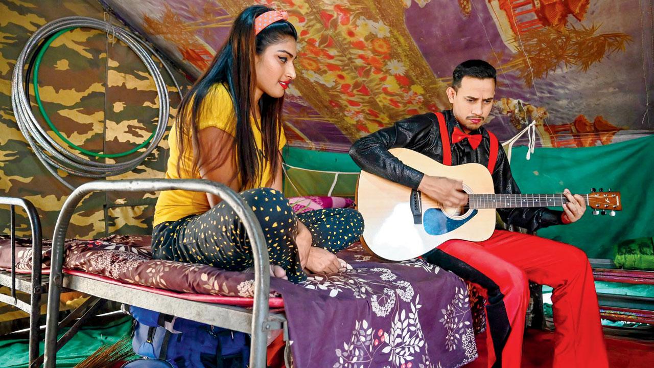 An artiste plays his guitar backstage while his colleague listens