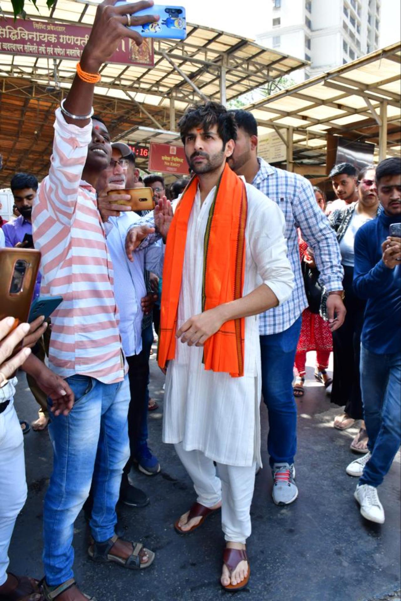 Kartik Aaryan was seen in a white kurta pyjama and a orange scarf around him. He was also seen clicking selfies with his fans