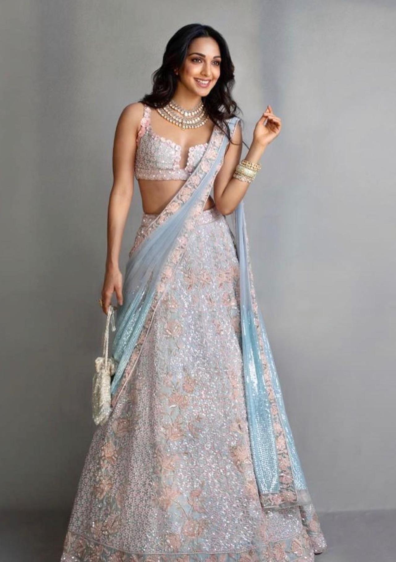 Beauty in Blue
Keeping up with her fetish for blingy and shimmery lehengas, the 'Bijlee Bijlee' hitmaker stole thunder when she rocked a pastel blue embellished lehenga for a star-studded wedding in Mumbai. A masterpiece by Manish Malhotra, Kiara's pastel blue lehenga had a sleeveless peach embroidered blouse with 3D floral patches. The combination of blue and peach made her ensemble stand out and enhanced Kiara's beauty and elegance to a whole new level. The dupatta with floral embroidery added subtlety to her extravagant embellished ensemble. To accessories her glamorous wedding look, she opted for three layered necklaces. Kiara ditched earrings and instead stacked up chunky statement kangans. The B-town beauty kept her hair open and paired nude makeup with the elegant outfit. 
 