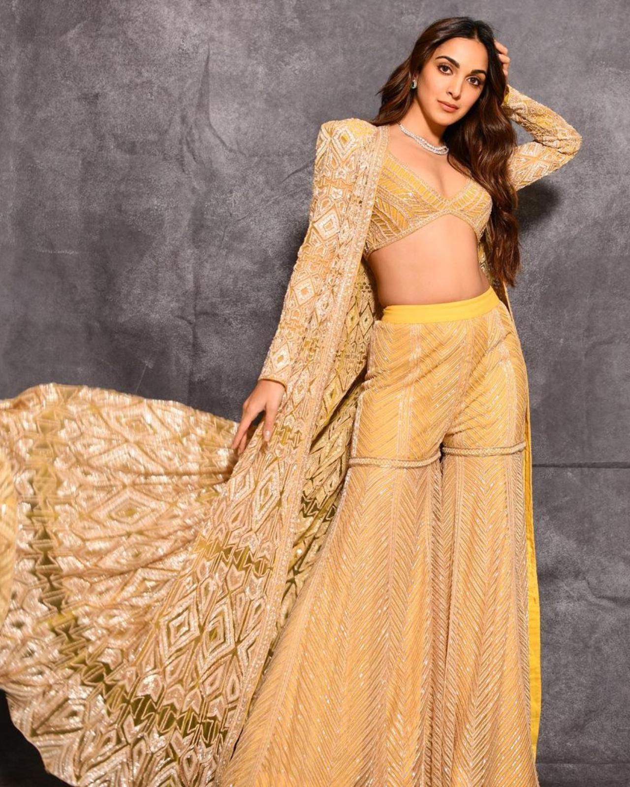 Slaying in Sharara
The 'Jugjugg Jeeyo' star who has been serving us stunning and steal-worthy ethnic looks for a long time made heads turn when she pulled off a bespoke sharara set at one of her friend's wedding. Advani's pastel yellow sharara set by Ritika Mirchandani was way different from the conventional sharara sets. The bralette style blouse and fit and flared pants gave a modern spin to her otherwise traditional sharara. Kiara looked like an absolute boss babe as she paired up her blouse and pants with a long embellished jacket. The intricate embroidery and embellishments in herringbone patterns added much-needed drama and playfulness to her pastel-yellow ensemble. To complete her one-of-a-kind ethnic look, Kiara opted for a double-layered diamond necklace and chunky diamond studs. Painting the town yellow, Kiara channelled her inner glam queen as she struck a magical pose for the camera. A pastel yellow embellished sharara set just like Kiara's would be a perfect fit for sangeet and cocktail parties, what say girls?
 