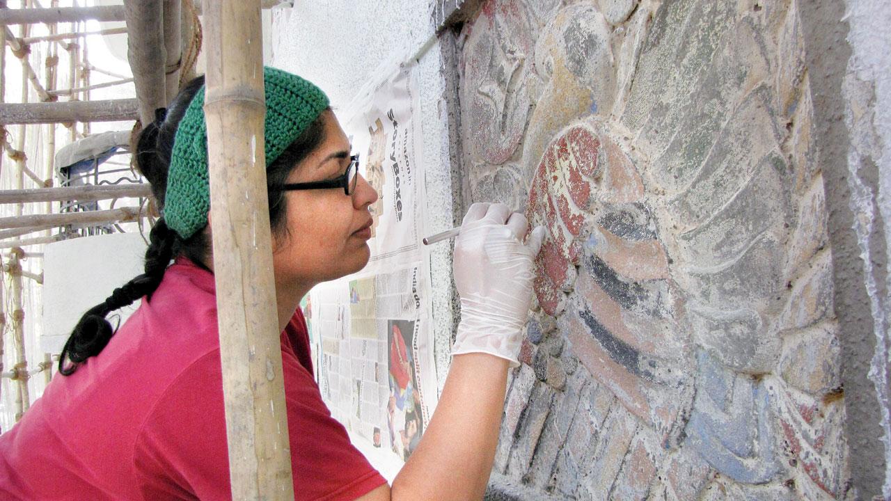 Nityaa Lakshmi Iyer cleans the bas-relief to expose a rich layer of colours. PIC/ART DECO TRUST MUMBAI