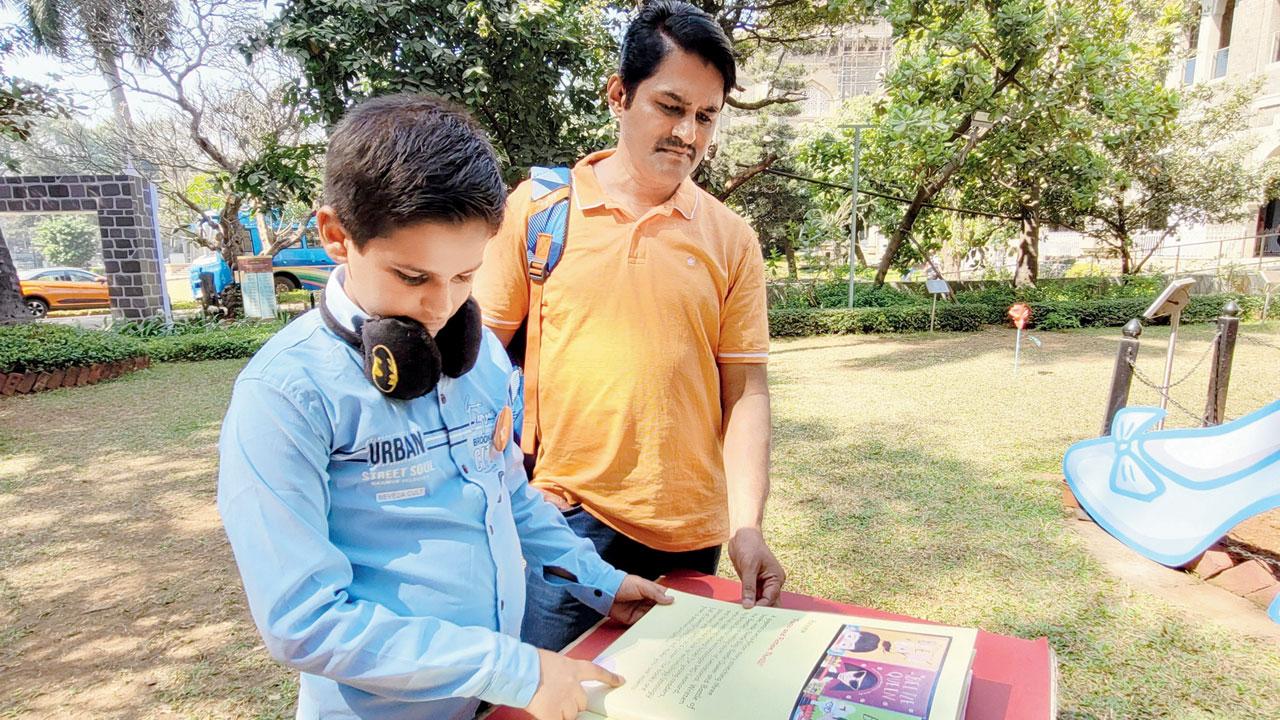 A young boy from Kalyan flips through the Book of Reviews in the garden leading up to the Children’s Museum