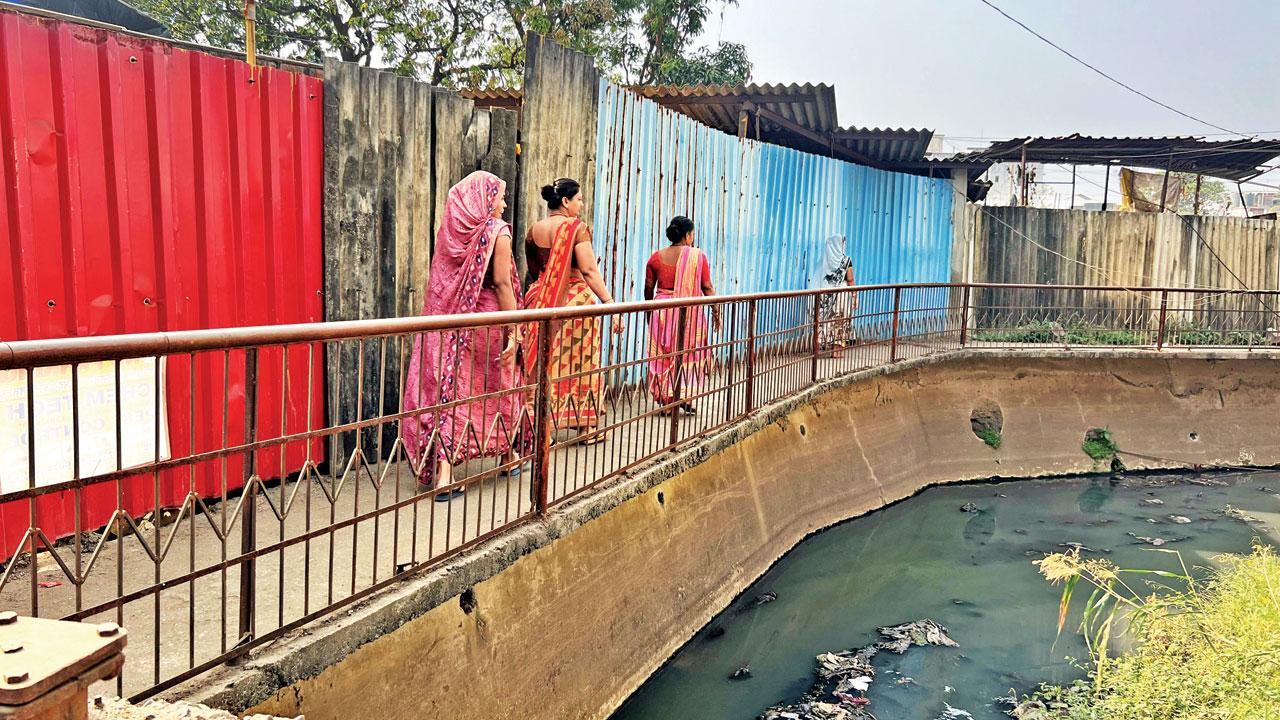 Women walk across the gutter on which the toilets are constructed. Pics/Hanif Patel