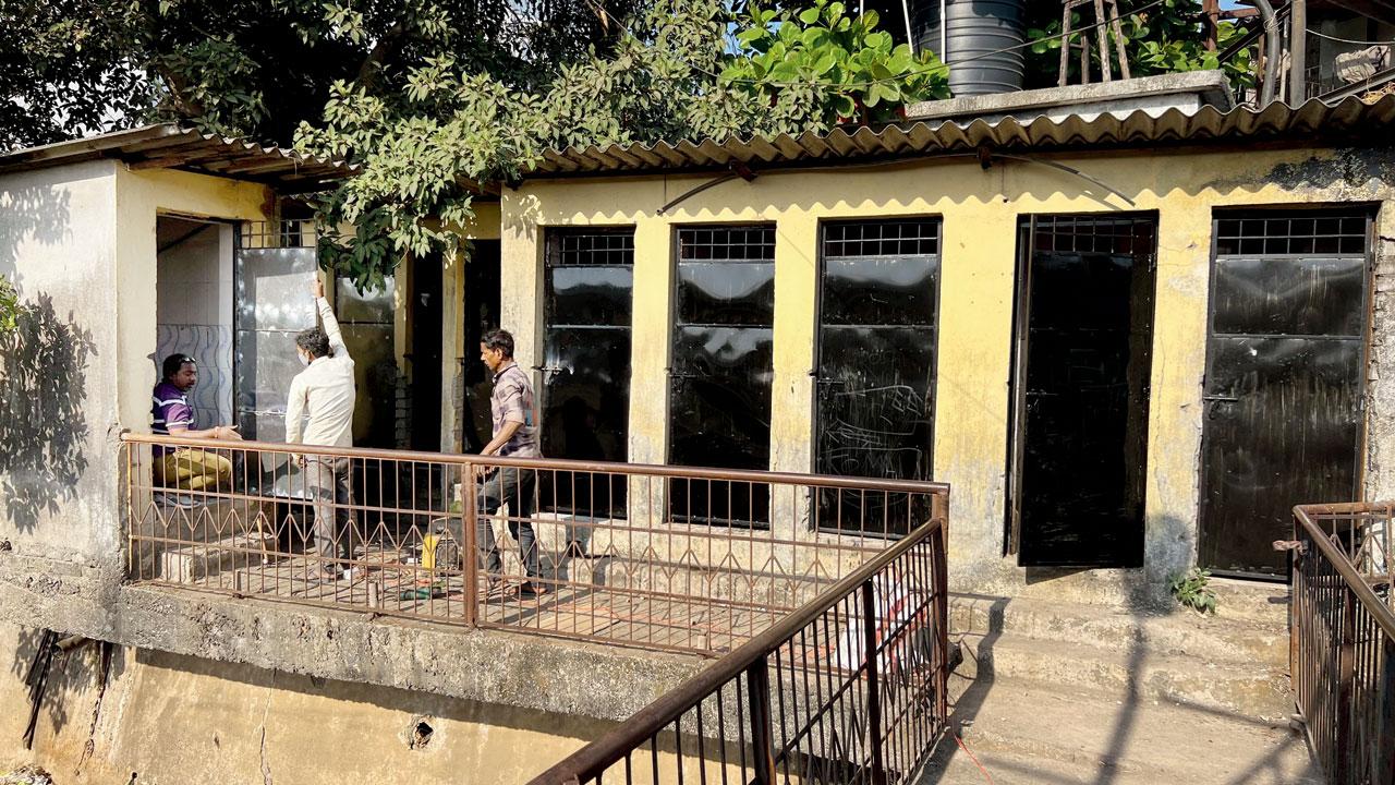 Workers attach the iron doors to the squat toilets at Sant Jalaram Bapu Nagar chawl in Vasai East on Sunday. Pics/Hanif Patel