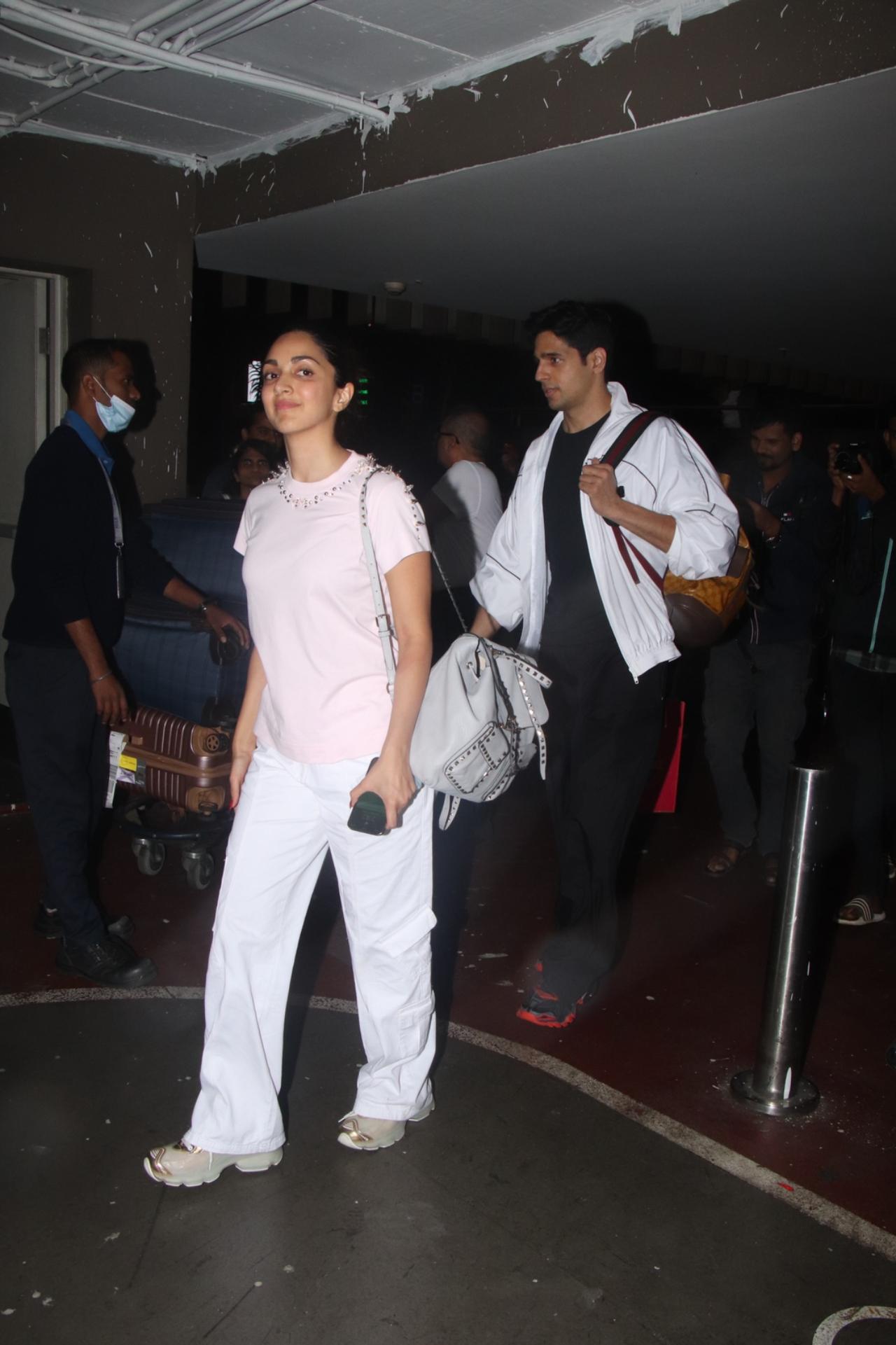 Both were dressed in casuals for their flight back home. While Kiara Advani was seen wearing a pastel pink tee with white pants, Sidharth sported an overall black outfit with a white tee