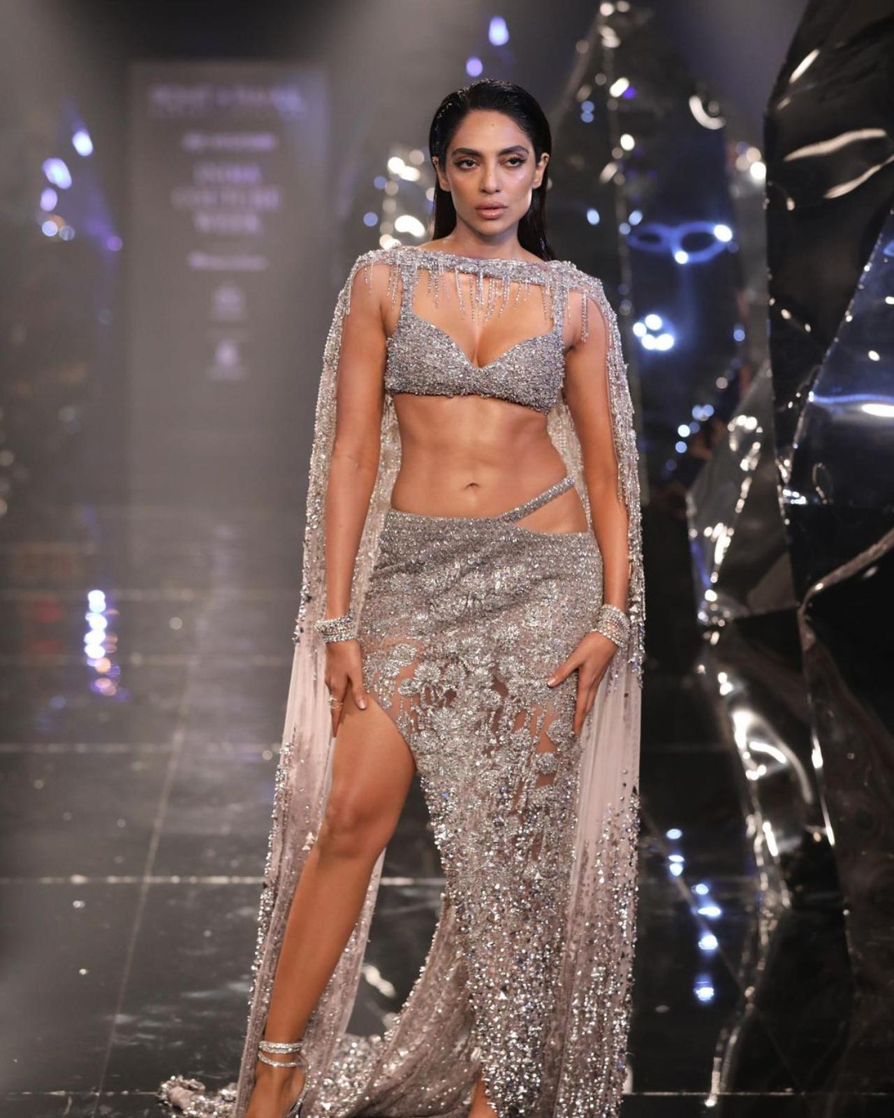 Sobhita Dhulipala dominated the runway in a glamorous, contemporary silver lehenga. Her outfit showcased a sequin-embellished bralette blouse with a midriff-revealing cut and fitted bust, paired with a sequined skirt featuring a sheer overlay, thigh-high slit, and floor-length hem. Her ensemble was gracefully completed with a sheer, tasseled dupatta with sequin embroidery, lending a refined touch to her look