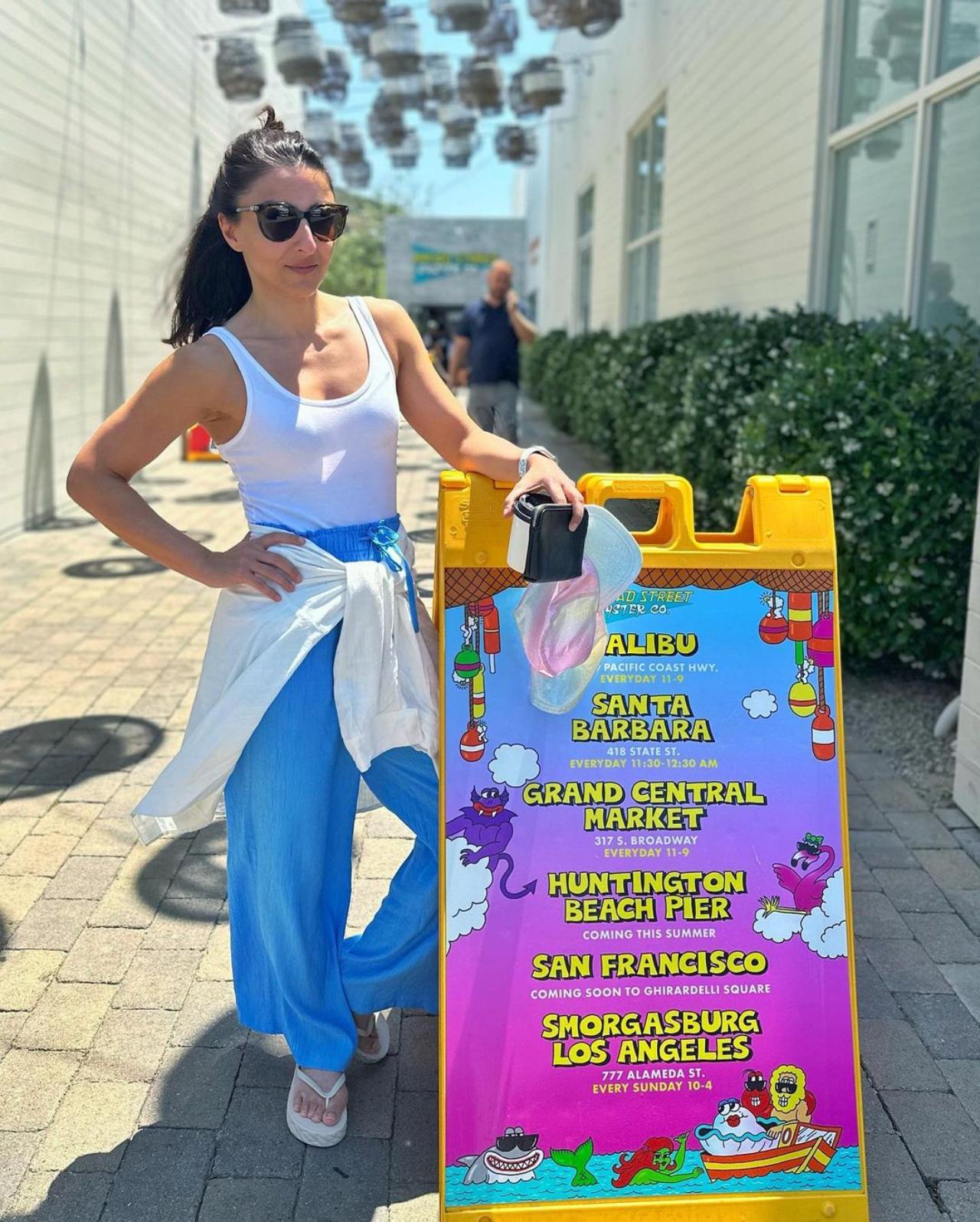 In a white tank top and sea-blue palazzo, Soha poses against what seems to be their itinerary in the USA
