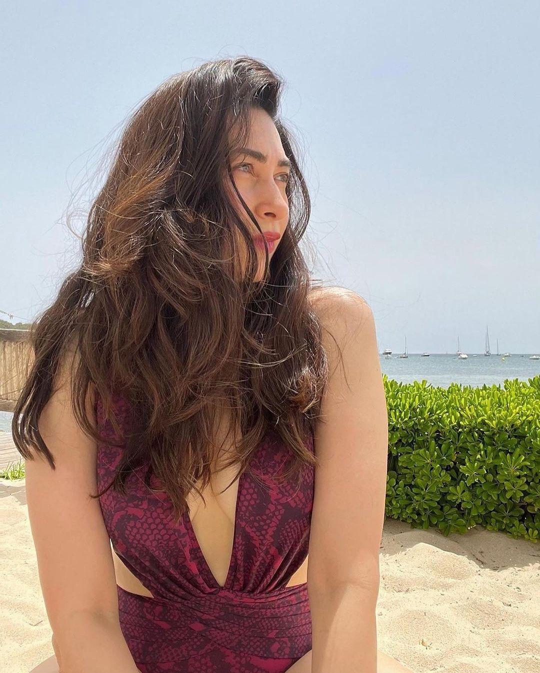 Karishma stuns in a vibrant purple one-piece swimsuit, effortlessly capturing the essence of poolside glamour    