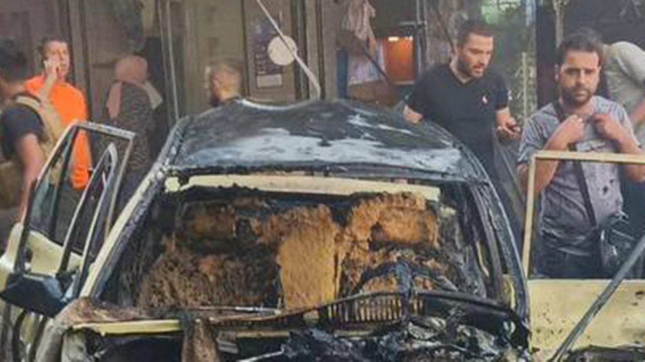 Photos shared by Al-Ikhbariya and pro-government media show a charred taxi surrounded by large crowds of people and men in military fatigues. Green, red and black Ashura flags and banners hung from buildings in the area.