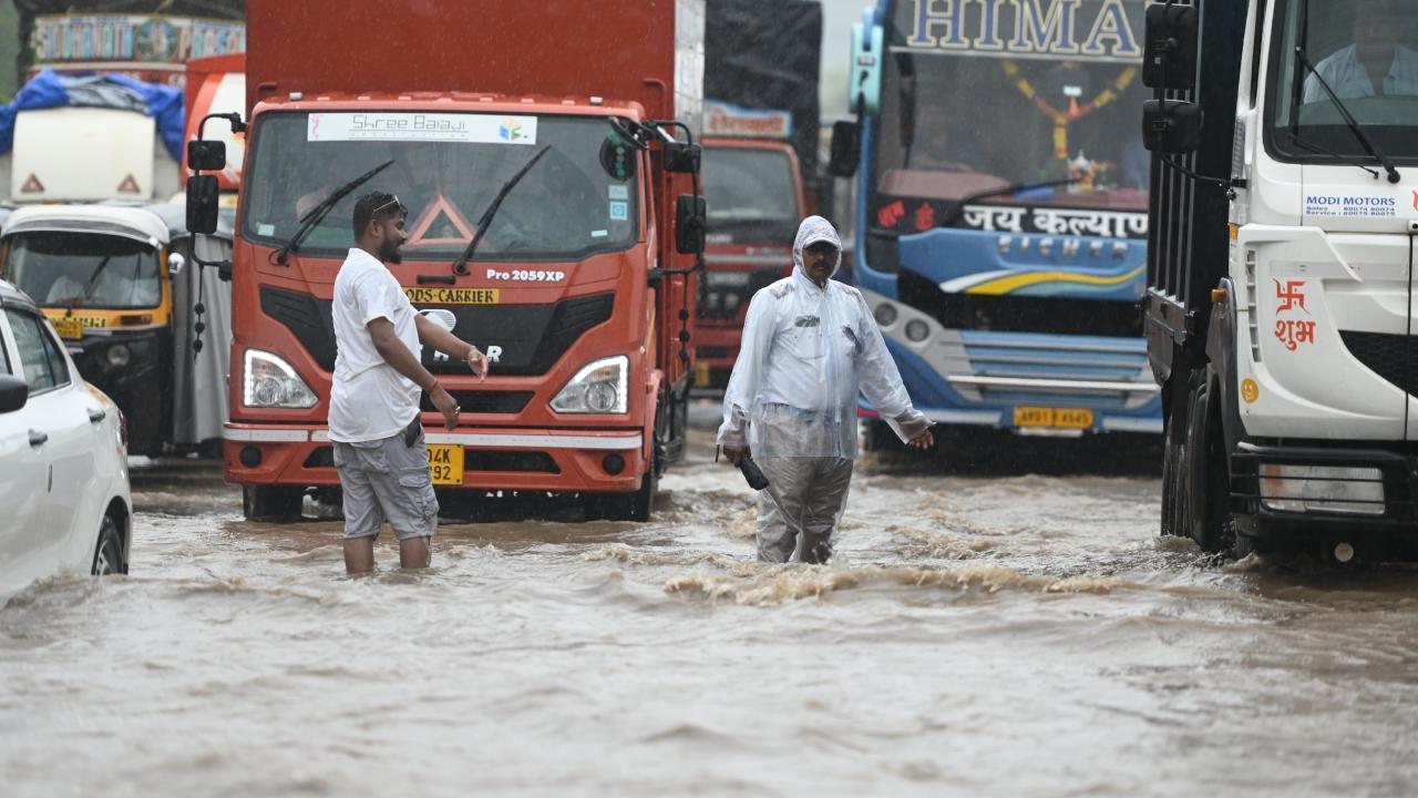 A traffic police personnel works on the flooded highway due to rains. Pics/Hanif Patel