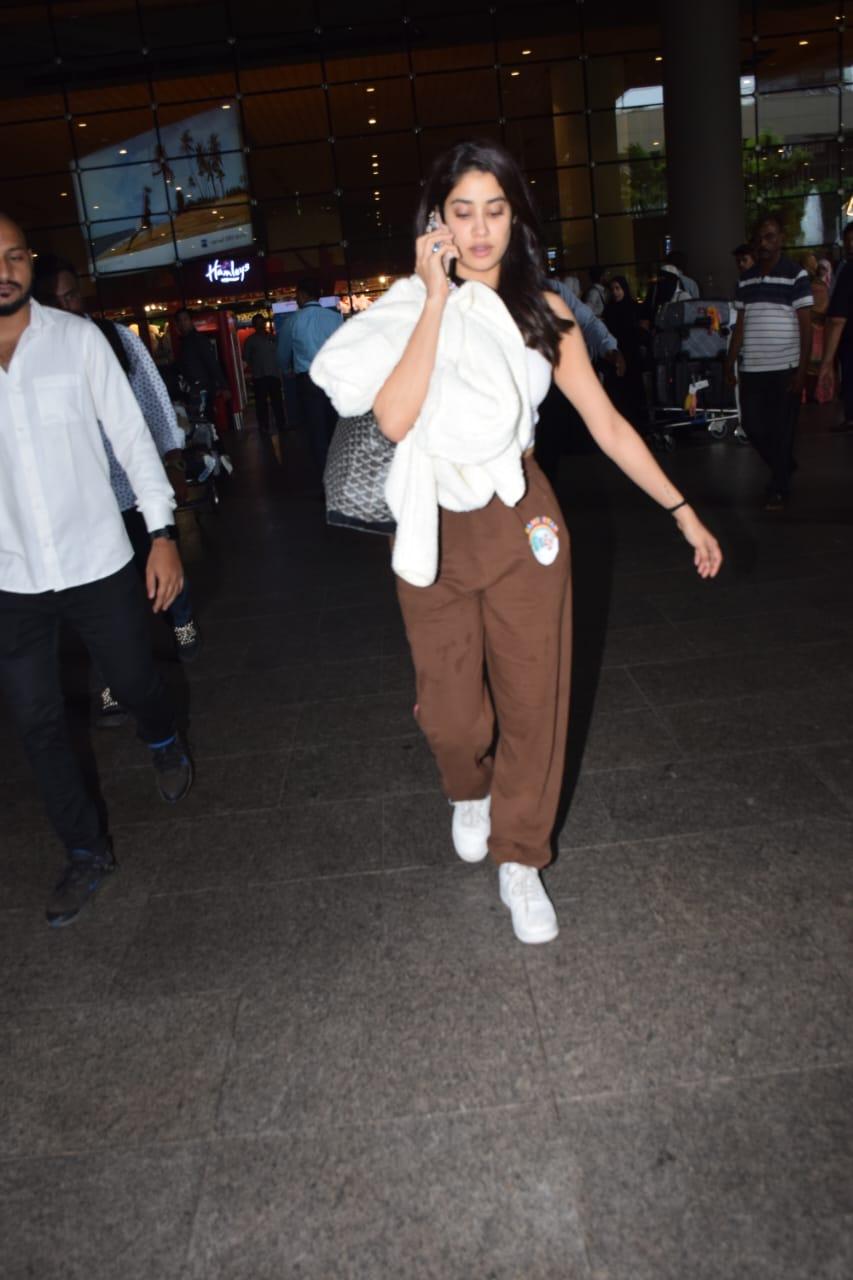 She sported brown sweatpants and a white tank top, radiating effortless charm. 