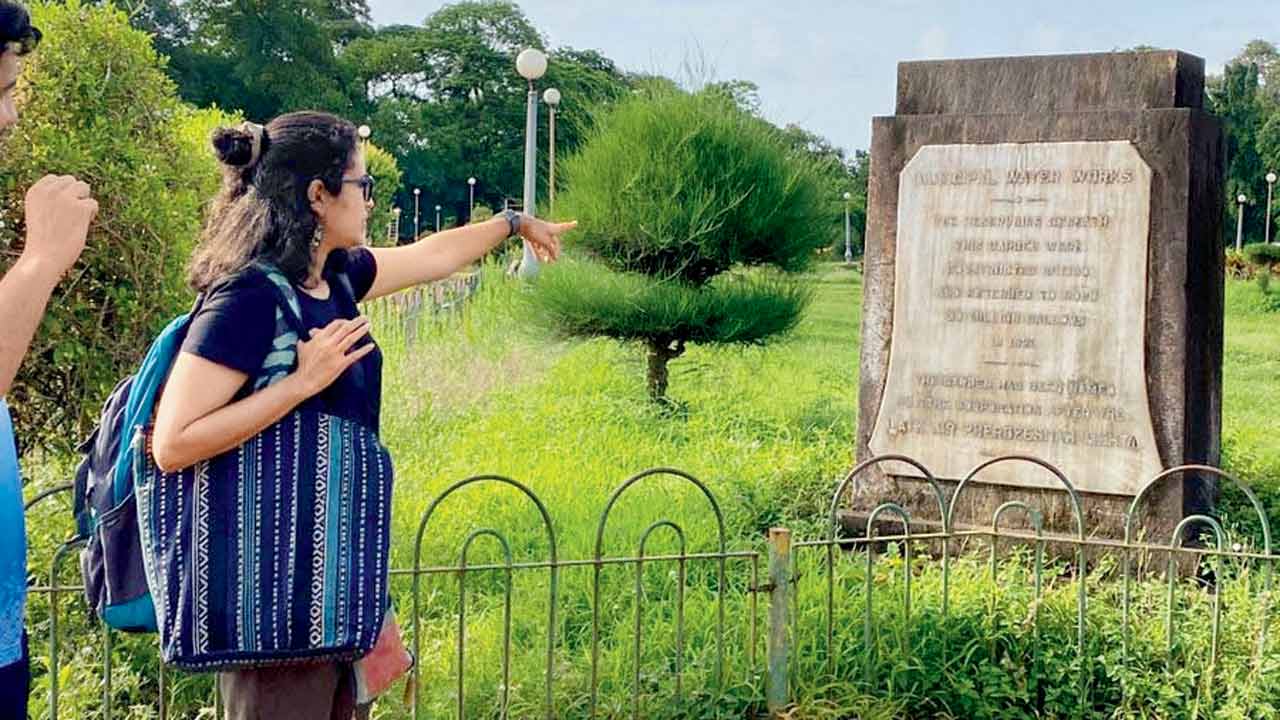 Akanksha Gupta points at a municipal water works stone plaque at Hanging Gardens
