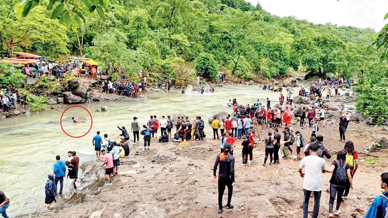 A trek guide (circled) survives by clinging on to a rock