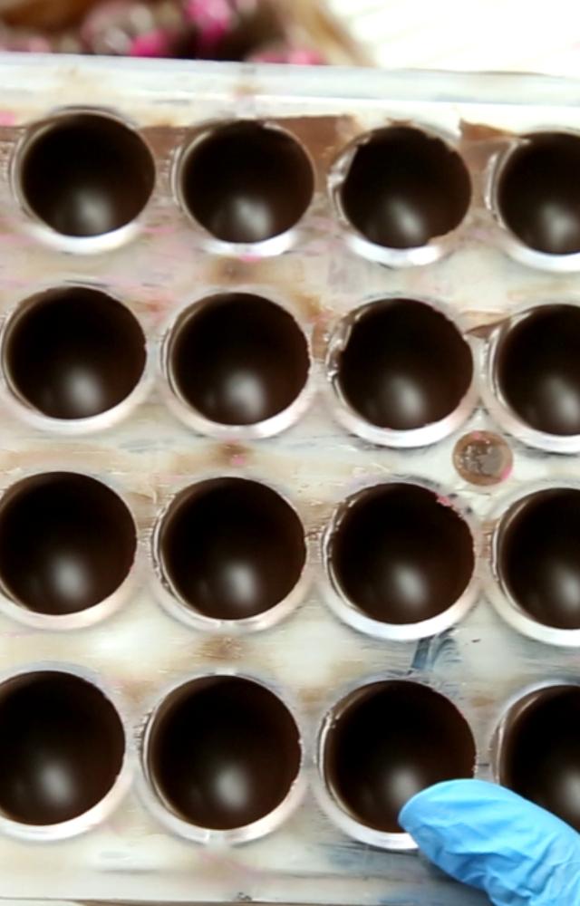 Post the method of tempering chocolate, the melted liquid is poured into shells. It is left to settle for a while to take the shape of the outer Bonbon cover