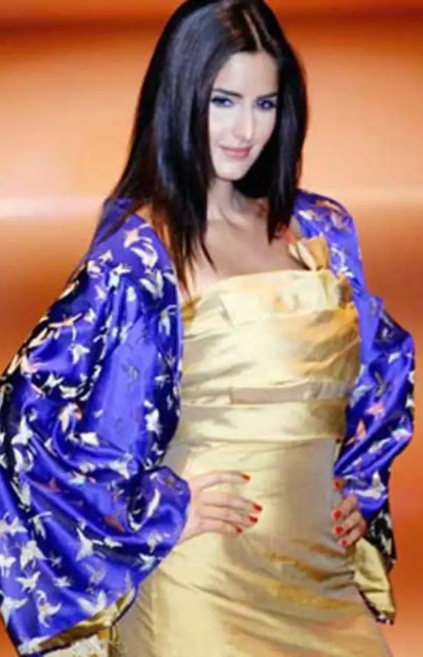 Katrina wears this golden dress and a contrasting oversized blue jacket that sets this look apart