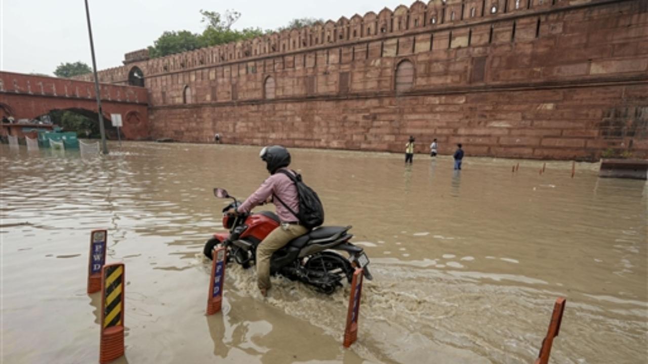 A motorcyclist wades through a flooded road near the Red Fort as the swollen Yamuna river floods low-lying areas, in New Delhi (PTI)