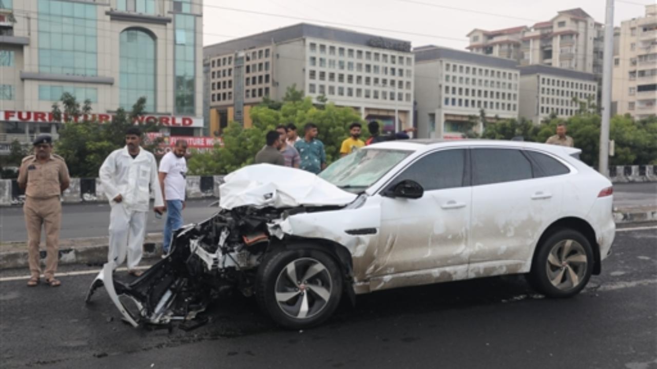People stand near the wreckage of a vehicle after an accident in Ahmedabad,Thursday, July 20,2023. At least 9 dead, 13 injured in a major accident involving multiple vehicles at ISKCON flyover
 