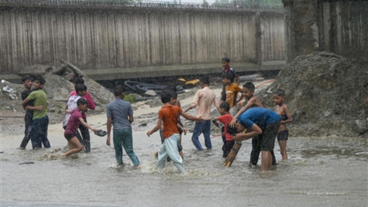 Children enjoy on a waterlogged street amid heavy monsoon rains in New Delhi (Pic/PTI)