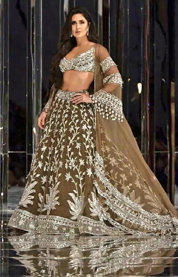 The ethereal beauty of Katrina Kaif shines bright as she glides down the ramp in a brown lehenga adorned with exquisite silver embroidery. A true vision of elegance!