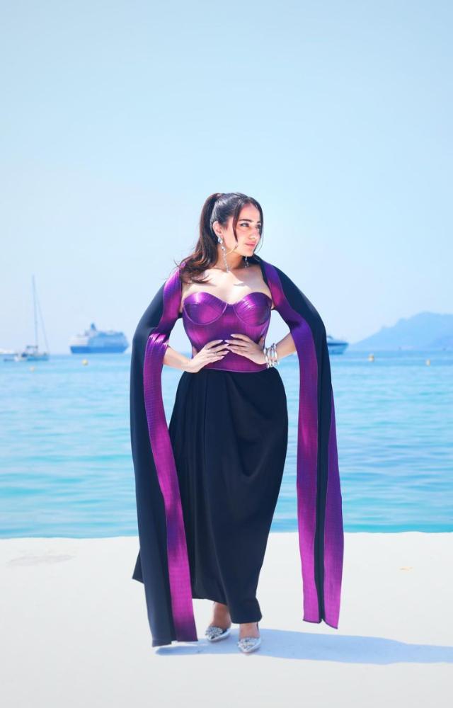 She wore a body-fit purple top with an illusion neckline and a black skirt. With dangling sea-blue earrings and a black-purple stole, the outfit `stole` the day