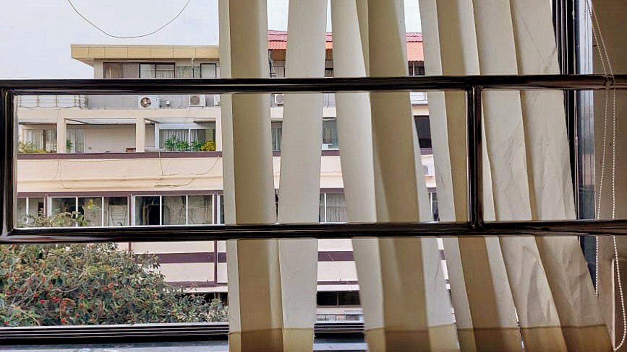 A window with broken and stuck shades in a room at the hostel