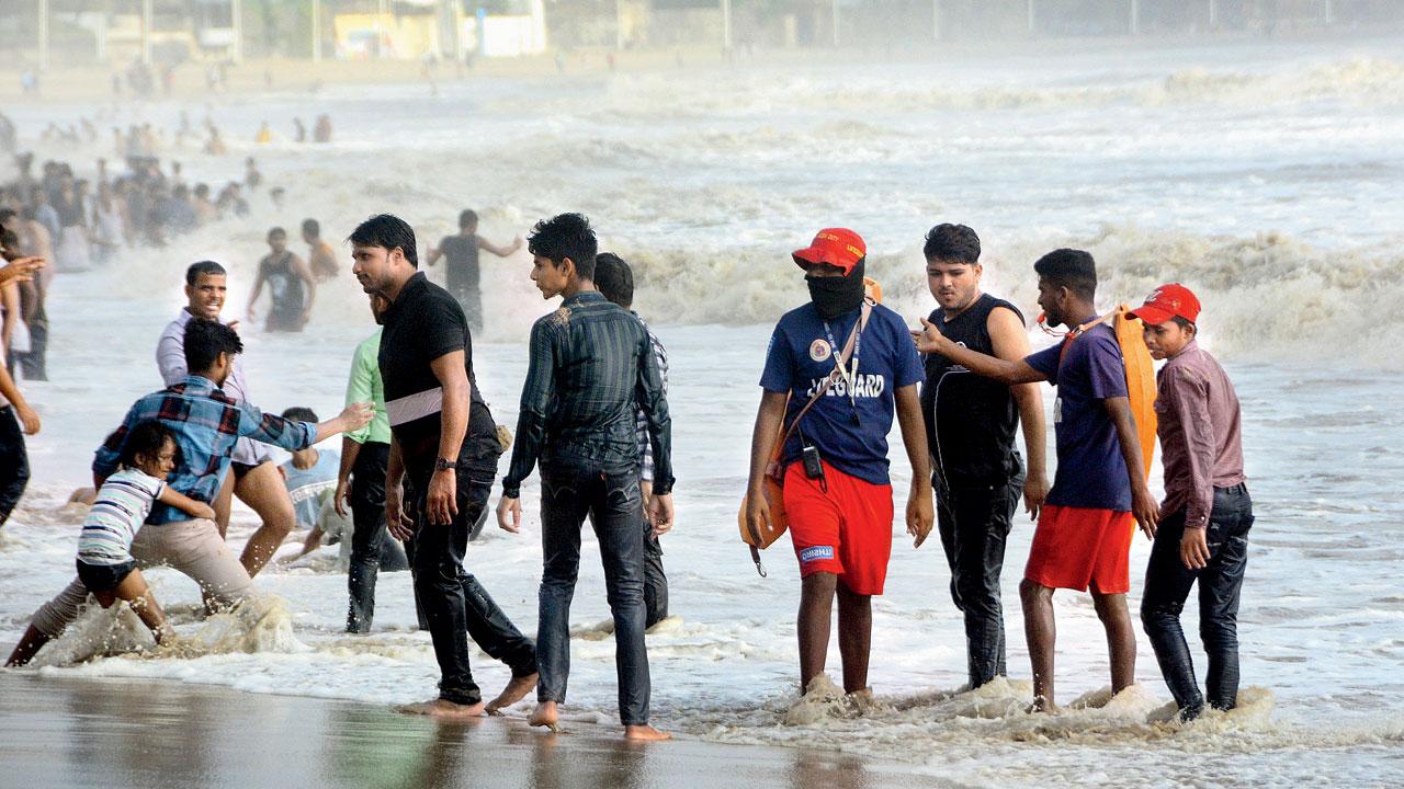 Mumbai police officers and lifeguards attempt to prevent people from venturing into the water at Juhu beach, on Monday. Pic/Satej Shinde