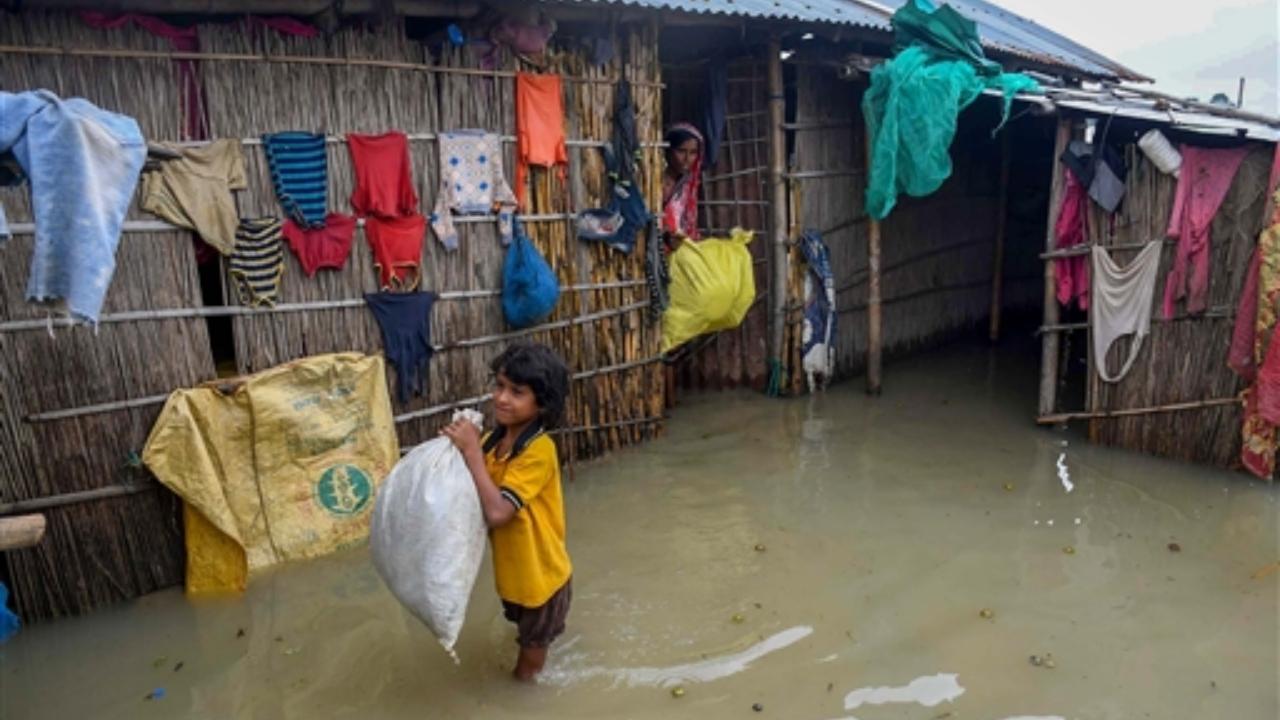 The Regional Meteorological Department has issued 'yellow' alert for Friday, asking people to be on watch and remain updated for heavy rainfall and thunderstorm in some parts of the state
In Pic: A woman and a child at their house in a flooded locality in Morigaon district of Assam
 