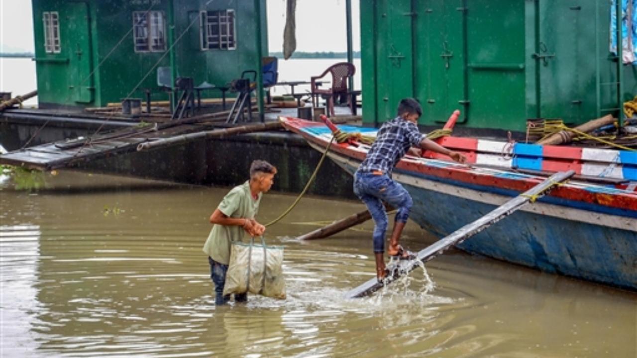 A Central Water Commission (CWC) report said the Brahmaputra is flowing above the danger level at Nematighat (Jorhat) and Dhubri
In Pic: Fishermen carry food and essentials to his boat on the flooded bank of the river Brahmaputra as it rains constantly in Assam
 