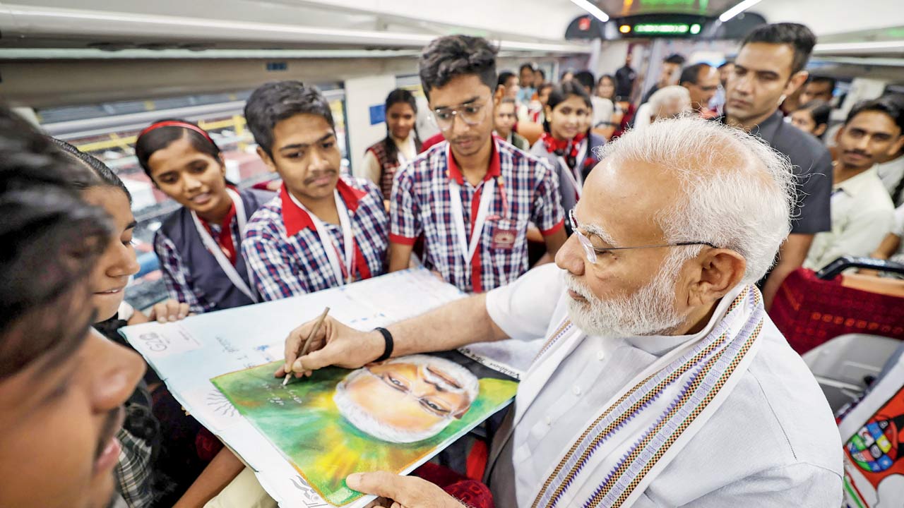 PM Narendra Modi signs a portrait of himself during the launch of Vande Bharat Express, in Bhopal. Pic/PTI