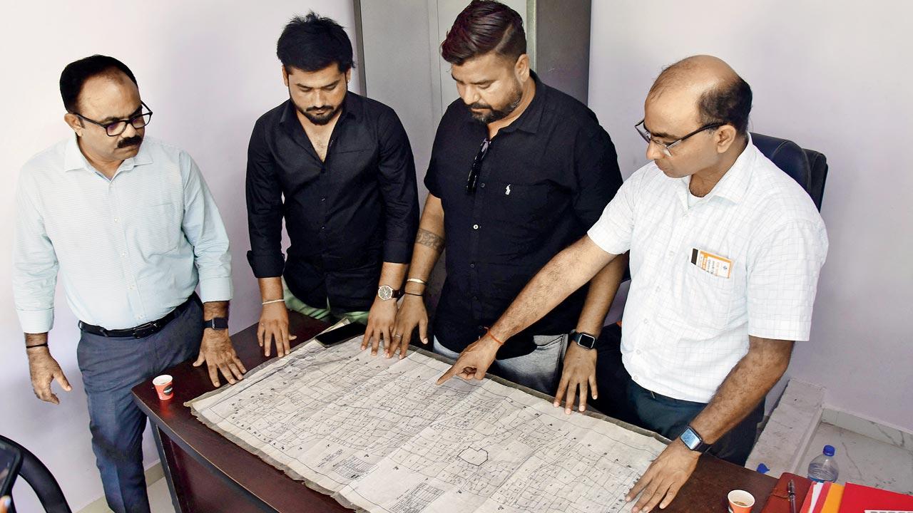 Antroli Sarpanch Umesh Rathod, deputy Sarpanch Vismay Solanki and the rest of the gram panchayat pores over a map of the village to map out the Bullet Train project