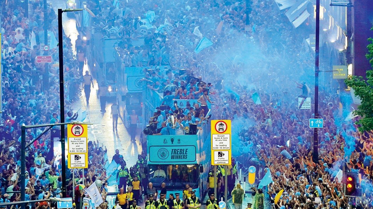 Man City players celebrate with all three trophies—Champions League, English Premier League and FA Cup—during a parade  on Monday. Pics/AP; PTI