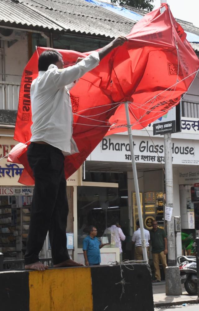 Traffic warden struggling with damaged umbrella during a stormy weather at Kabutar khana, Dadar. PIC/ASHISH RAJE