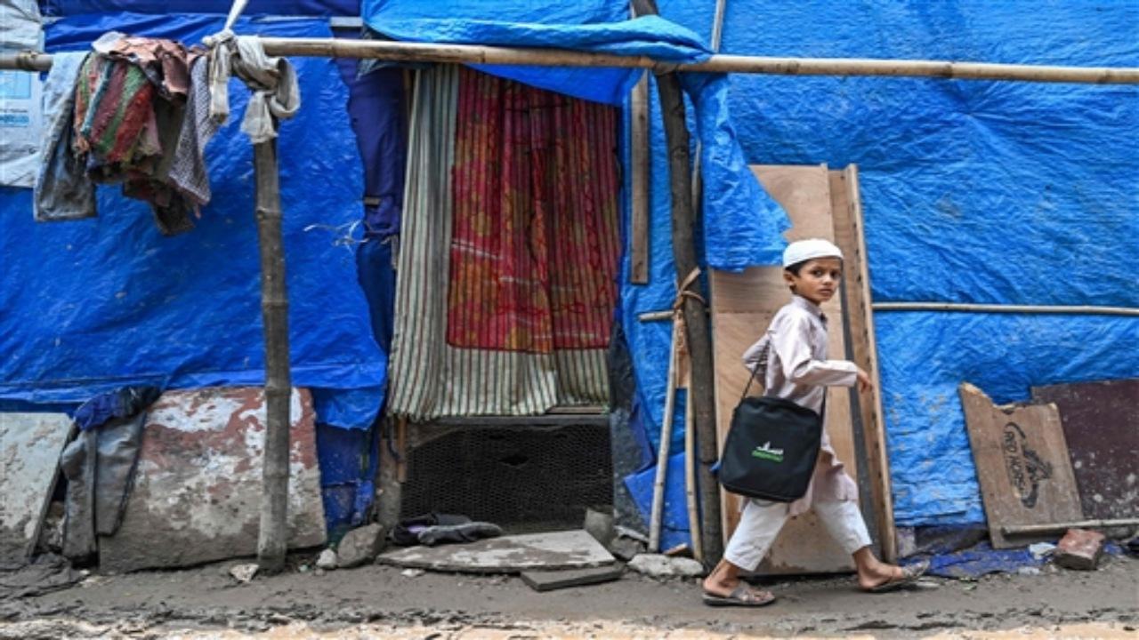 A Rohingya refugee boy walks along a street at a refugee camp on the World Refugee Day, in New Delhi on June 20, 2023. 