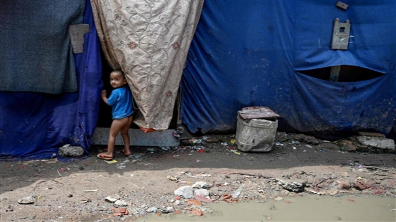 A Rohingya refugee child stands outside a makeshift shelter at a refugee camp on the World Refugee Day, in New Delhi on June 20, 2023. 