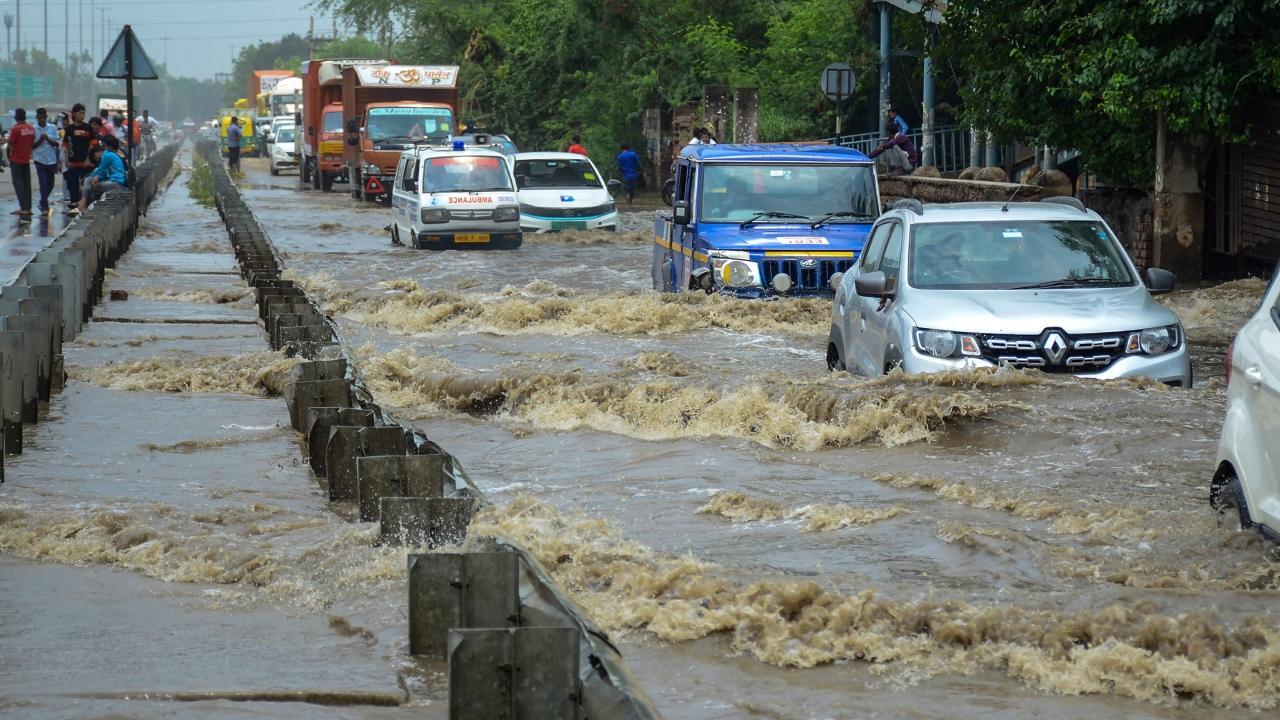 Vehicles move through the waterlogged Delhi-Gurugram Expressway service road following rain. Pics/PTI