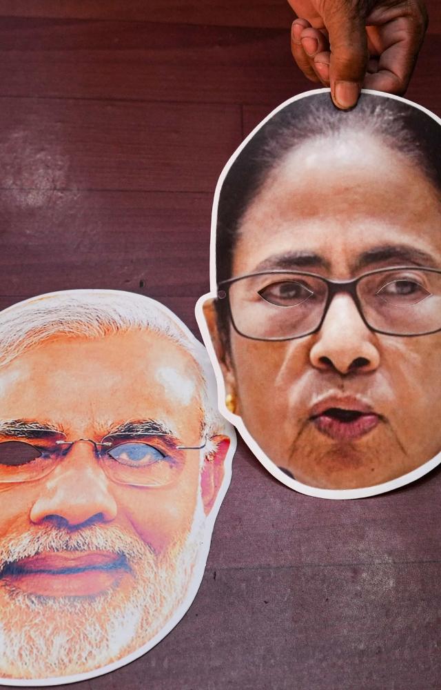 A shopkeeper displays face masks of different political leaders at a shop for sale ahead of the West Bengal panchayat elections
