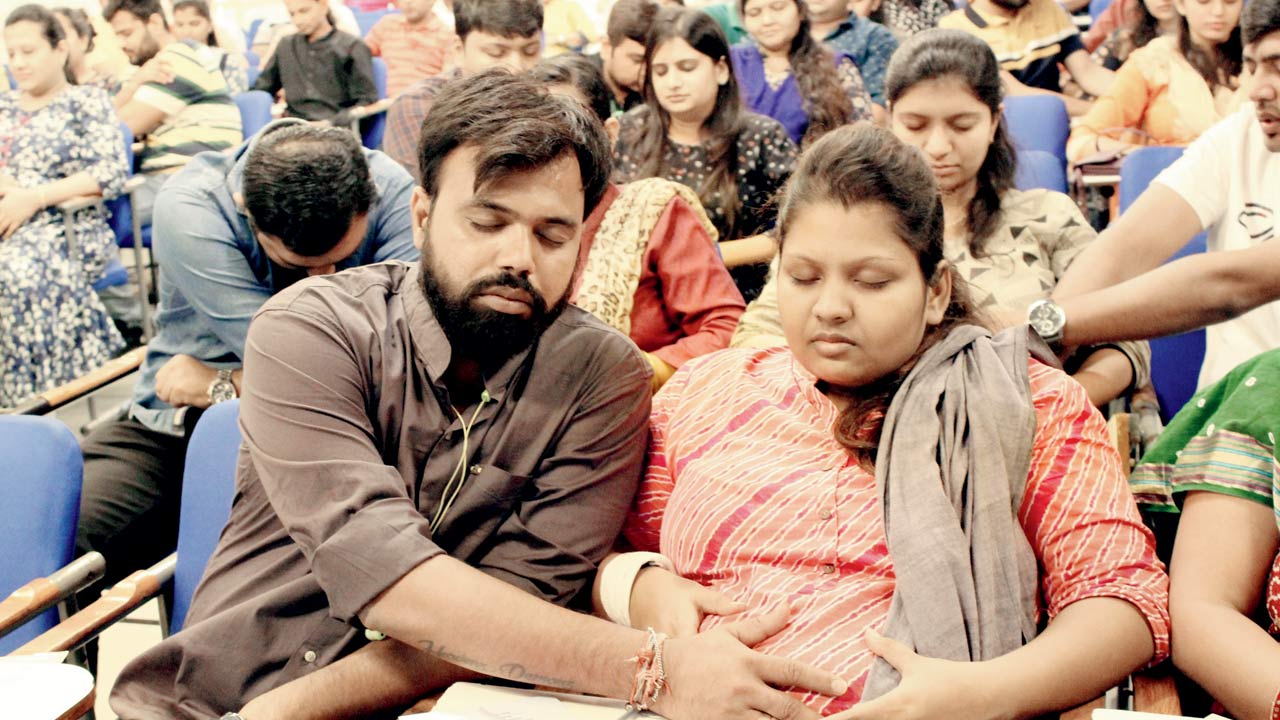 Parents seen participating in a garbh samvad workshop by Majestic Garbh Sanskar. The guided meditation session has parents talk to the unborn child