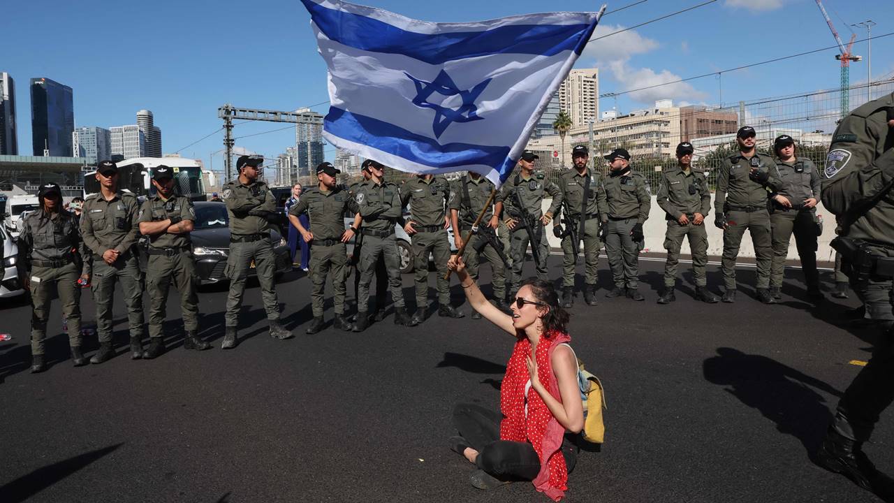 Israeli forces stand guard as a protester waves a national flag during a demonstration against the government's controversial judicial reform bill in Tel Aviv. Pic/AFP