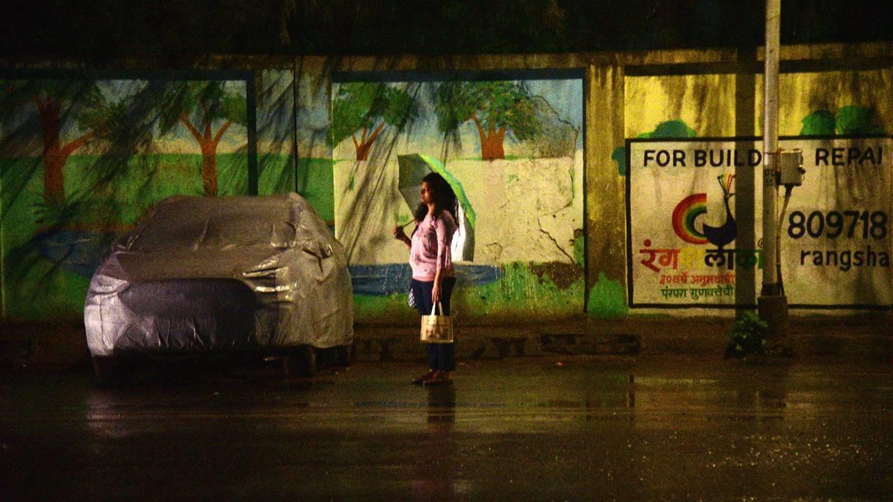 A woman holding an umbrella stands at the roadside amid rainfall in Mumbai's Sion on Thursday evening. Pic/Pradeep Dhivar