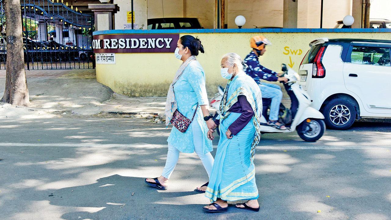 Women wearing masks walk past a society in Parel. Pic/Atul Kamble