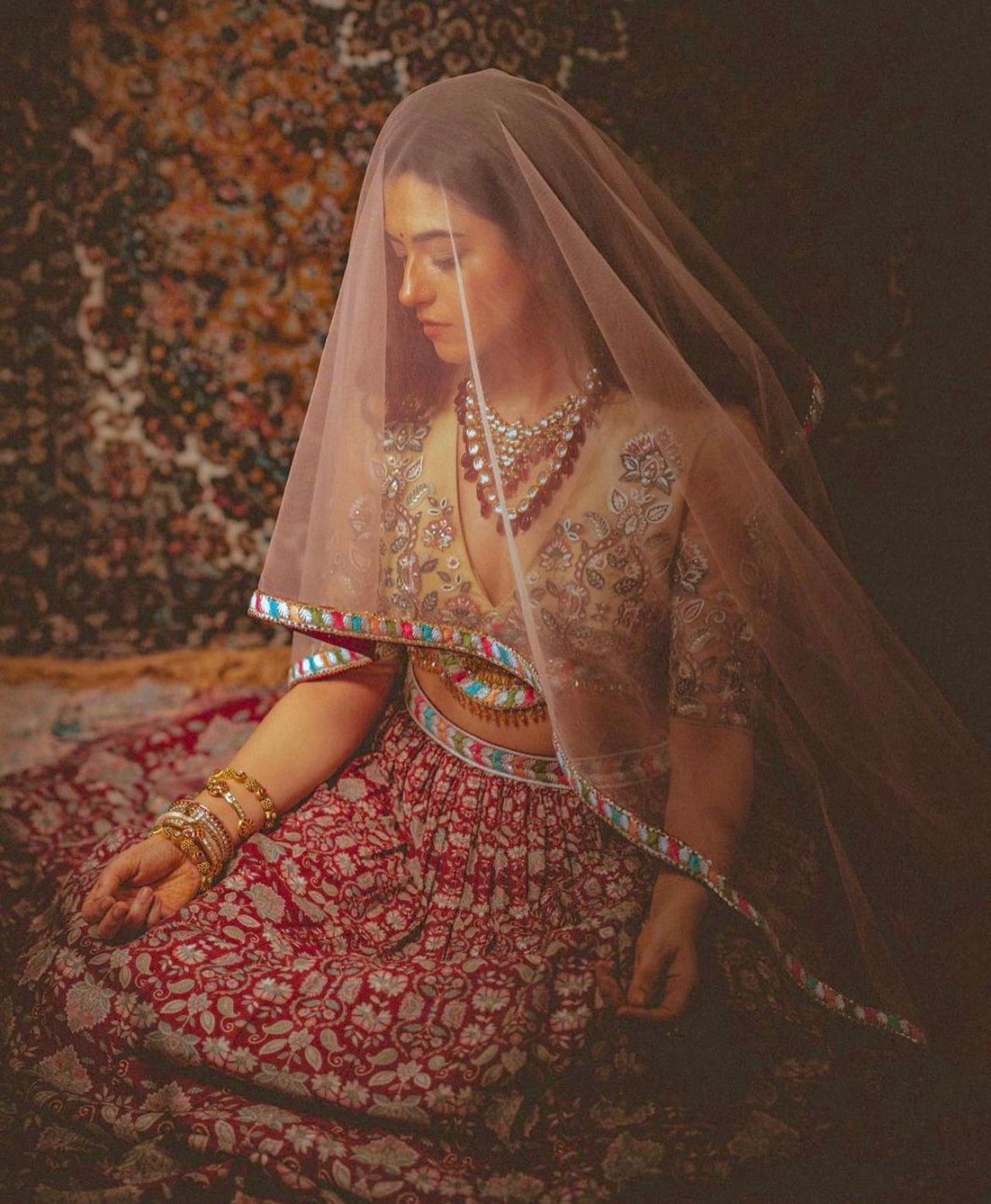 Lehenga
Here, Ridhi is seen wearing a heavy lehenga, with beige embroidered deep-neck blouse. She paired it with a heavy red beaded kundan necklace with a peach dupatta as a veil