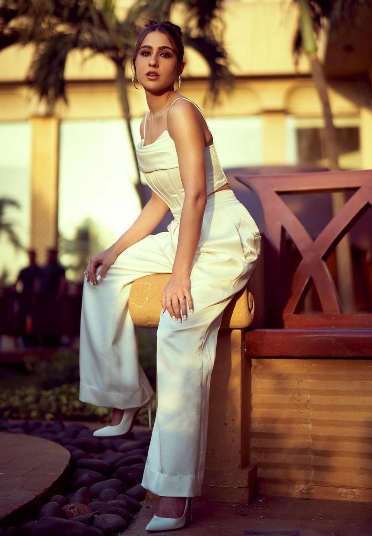 Sara Ali Khan oozes oomph as she dons a white corset-style satin crop top along with pleated wide-leg trousers. The actor looks like an absolute boss babe as she rocks white pointed-toe pumps with her all-white ensemble. While she glamorised her look with gold hoops and multiple rings, she simply slayed as she rocked subtle make-up. 
