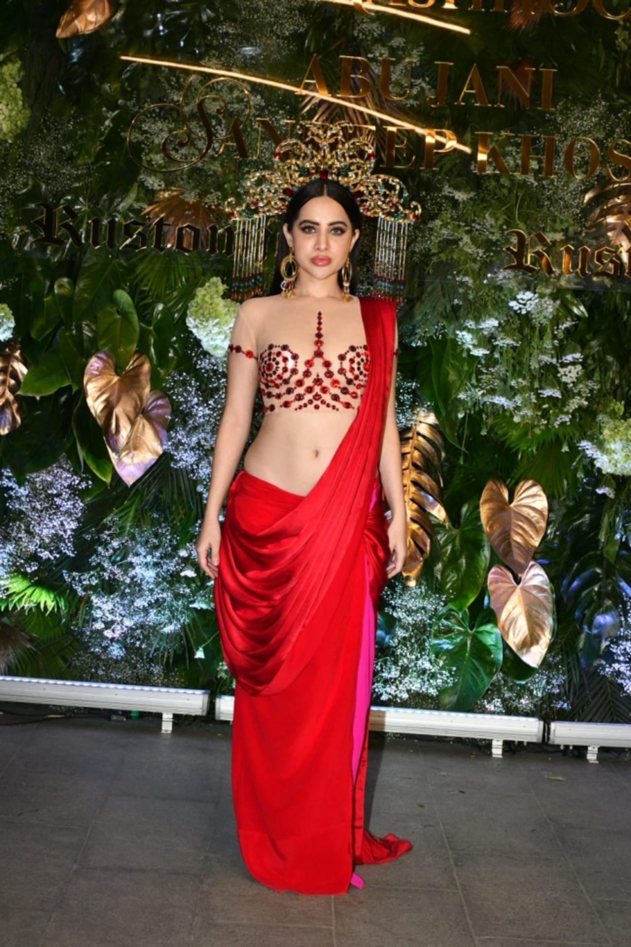 Social media star Uorfi Javed looked stunning in a bright red indo-western satin dress draped like a saree and a nude blouse with patterned red embellishments. The dress had a complimentary peak of hot pink on the side. Javed rounded off her look with a gorgeous 'Goddess' like head gear