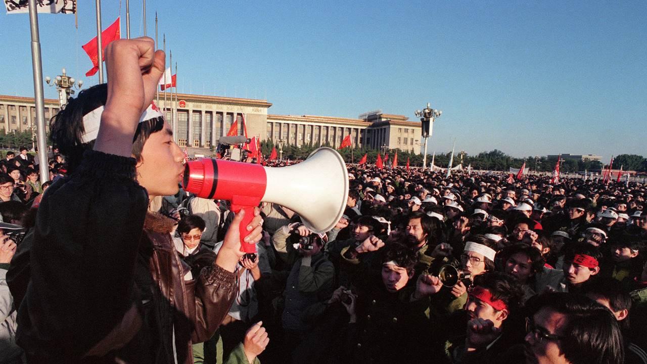 A young man with his fist raised uses a loudspeaker to address pro-democracy protesters gathered at Tiananmen Square in Beijing.