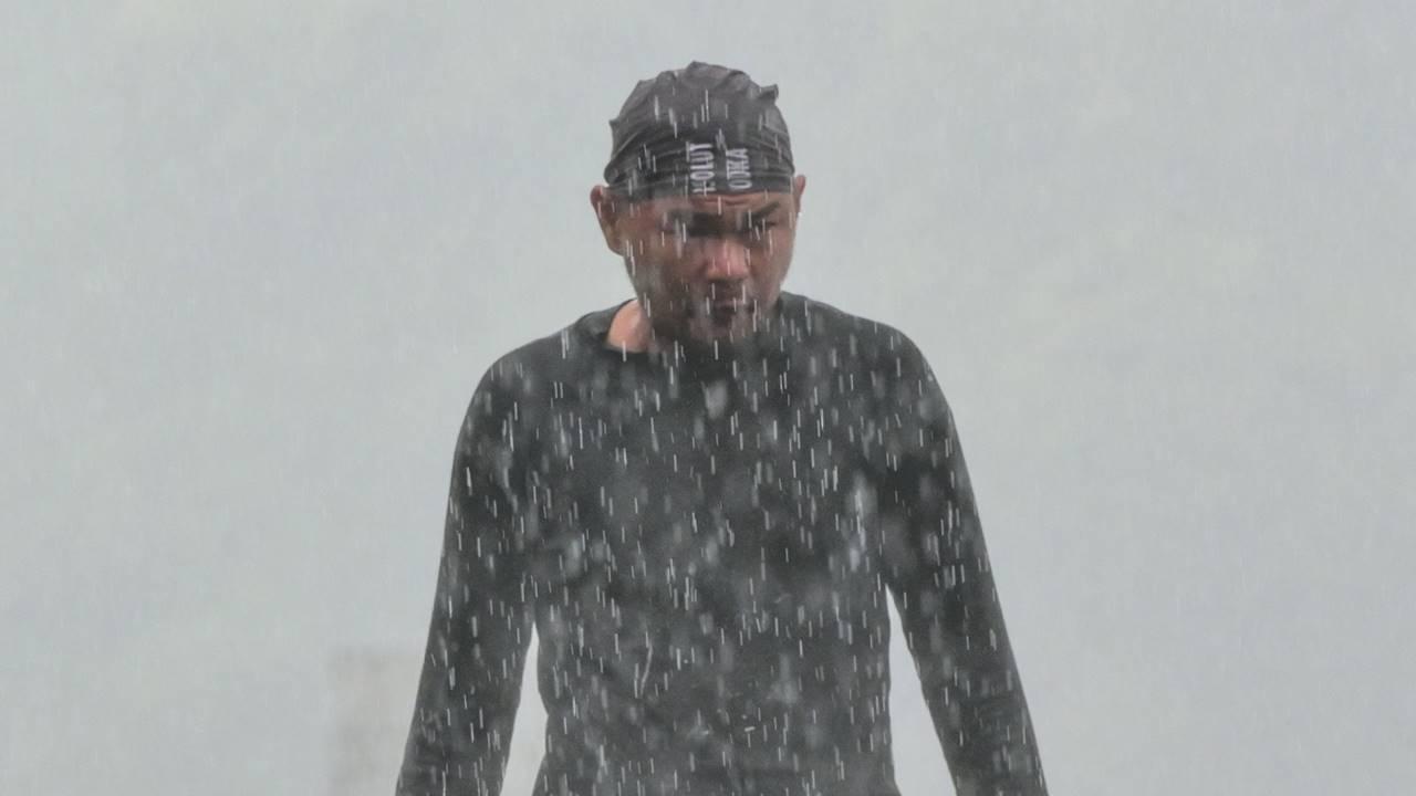 A man walks in the pouring rain on the river bank in New Taipei City.