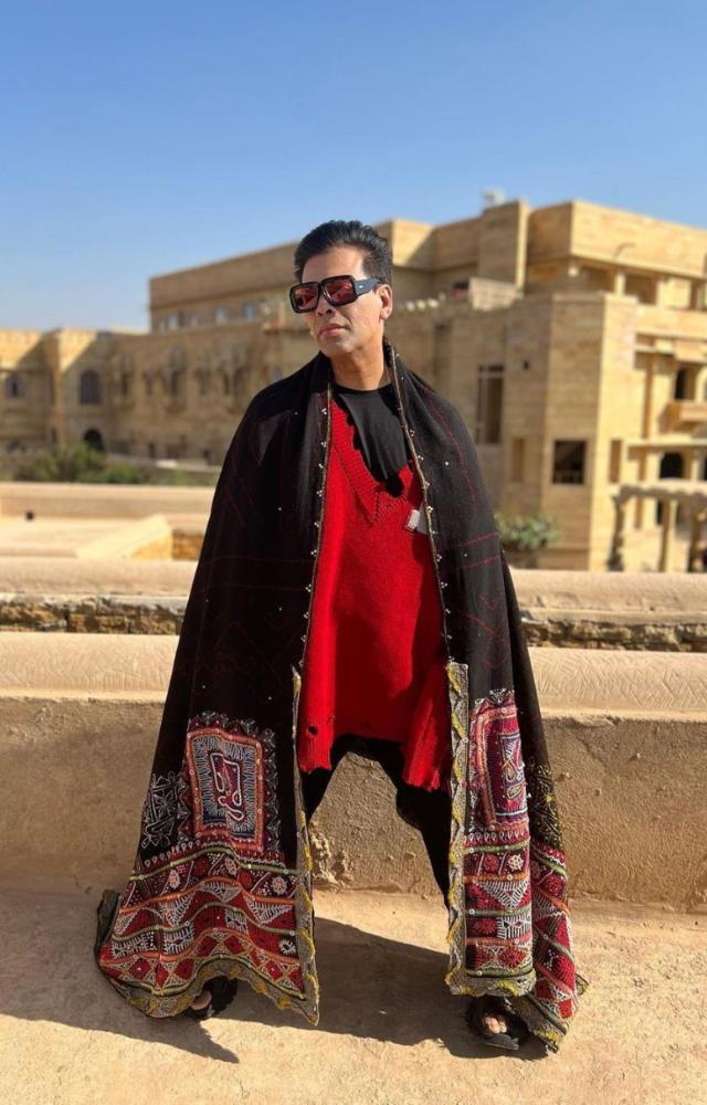 Karan Johar is seen wearing a shawl, and he is seen striking different poses in front of the camera.